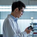 白衣を着た技術責任者が最先端の研究室で布地を調べている写真